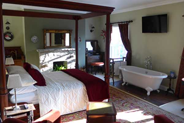 a large room with four poster bed and rolltop bath